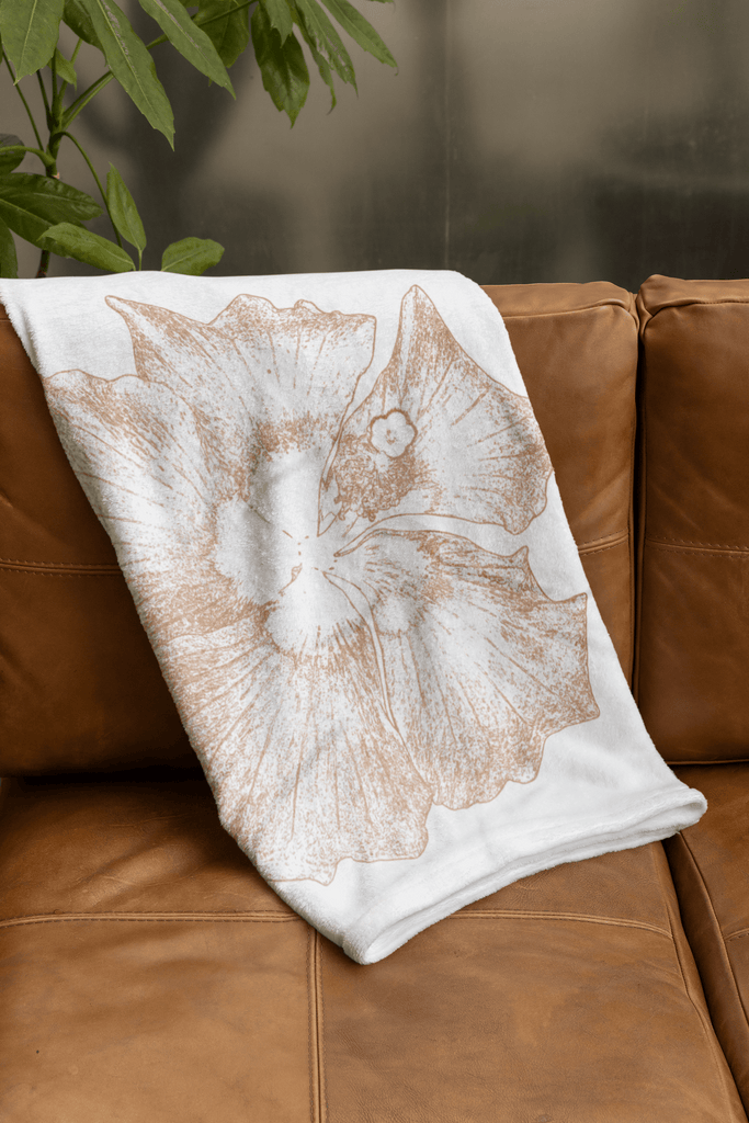 couverture dessin hibiscus pliée sur canapé cuir marron 