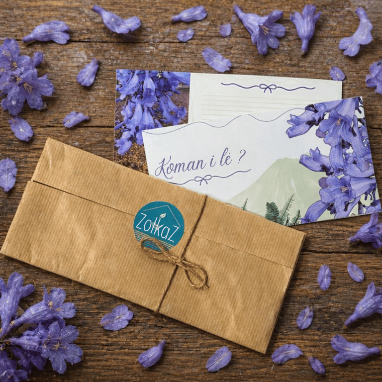 Carte de correspondance réunionnaise décorée de jacarandas violets et de montagnes, glissée dans une enveloppe kraft ficelée.